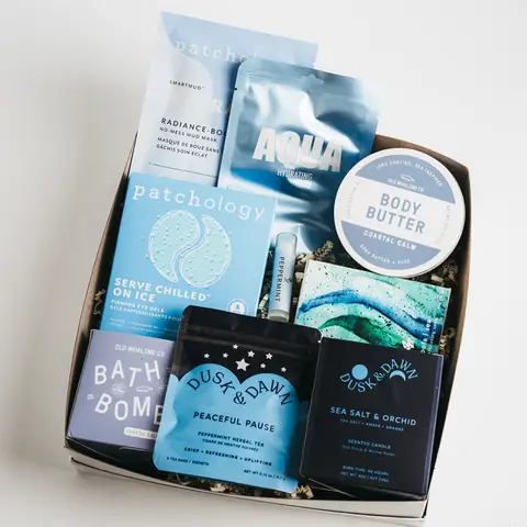 Gift box with spa items, bath bomb, body butter, eye gels, candle, tea, and peppermint oil