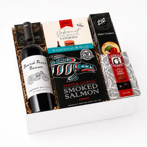 Gift basket with mark ryan wine, cookies, smoked salmon, and crackers on a marble surface